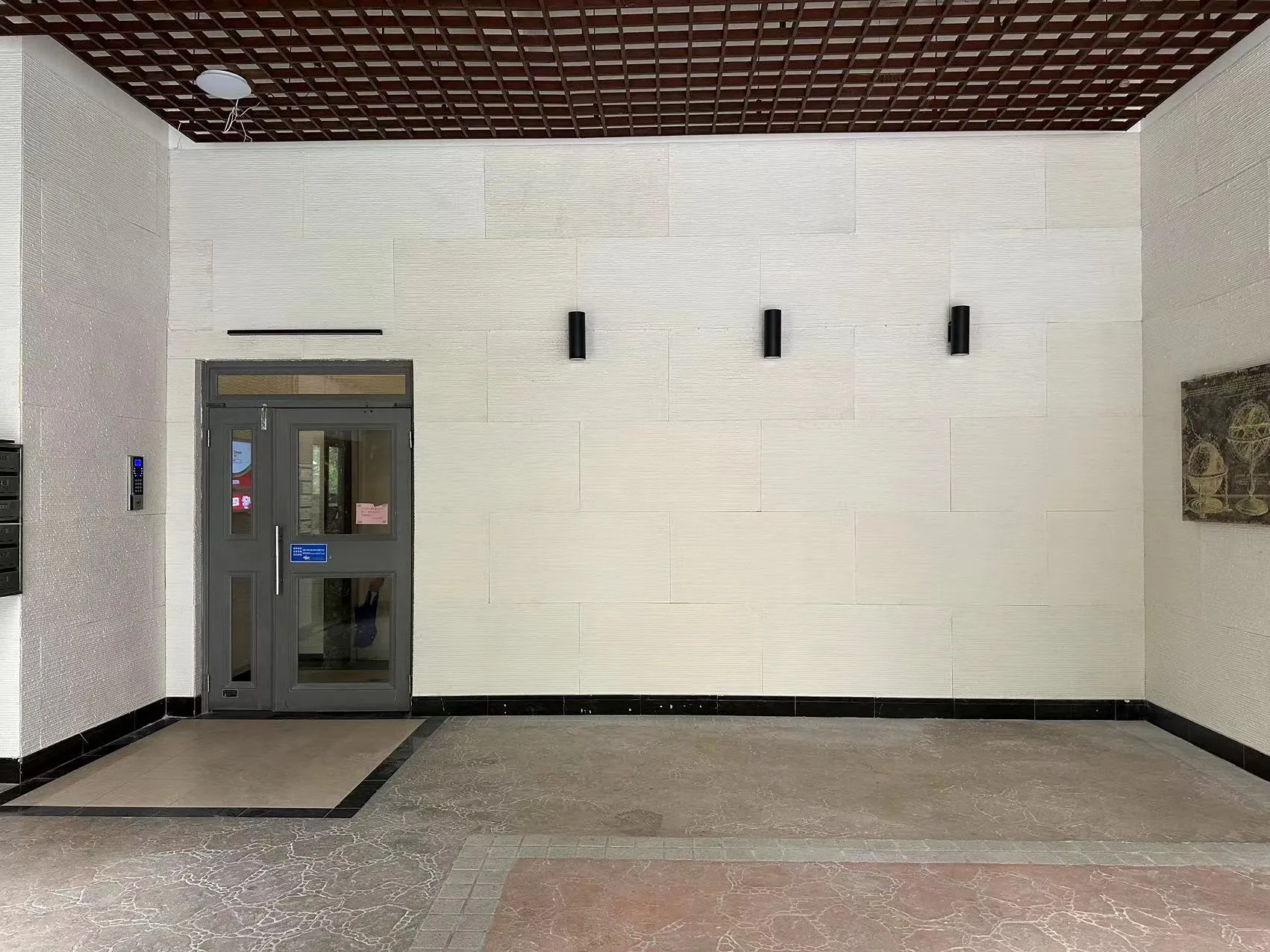 完工後的大廳，三盞黑色壁燈已就位、此時未點亮，地面清空，右側牆面掛上畫作
